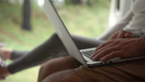 primer plano - una pareja sentada en la parte trasera de su autocaravana hablando y mirando una computadora