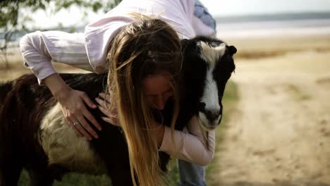 Woman-stroking-goat-outdoors,-caresses-it-with-both-hands