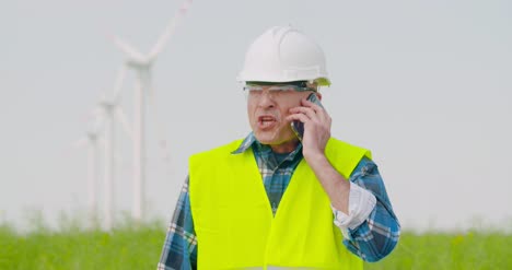 frustrated male engineer talking on phone at farm