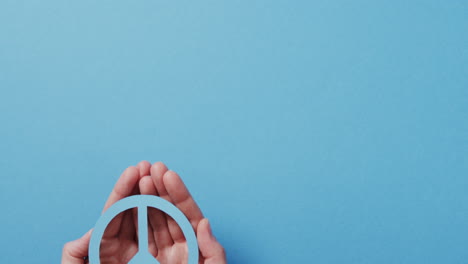 cerca de las manos de una mujer caucásica sosteniendo un signo de paz azul con espacio de copia en un fondo azul