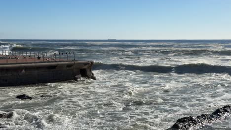 waves crashing against the sea point pool wall on a sunny winter’s day in sea point, cape town