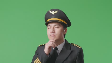 close up of asian man pilot thinking about something and looking around while standing in the green screen background studio