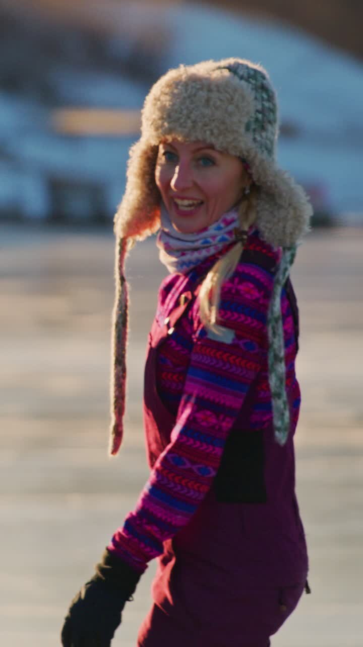 Gioiosa avventura invernale: una giovane donna con un vivace abbigliamento invernale sfida il freddo mentre pattina sul ghiaccio, circondata da un bellissimo paesaggio invernale, che rappresenta il divertimento e la libertà all'aria aperta