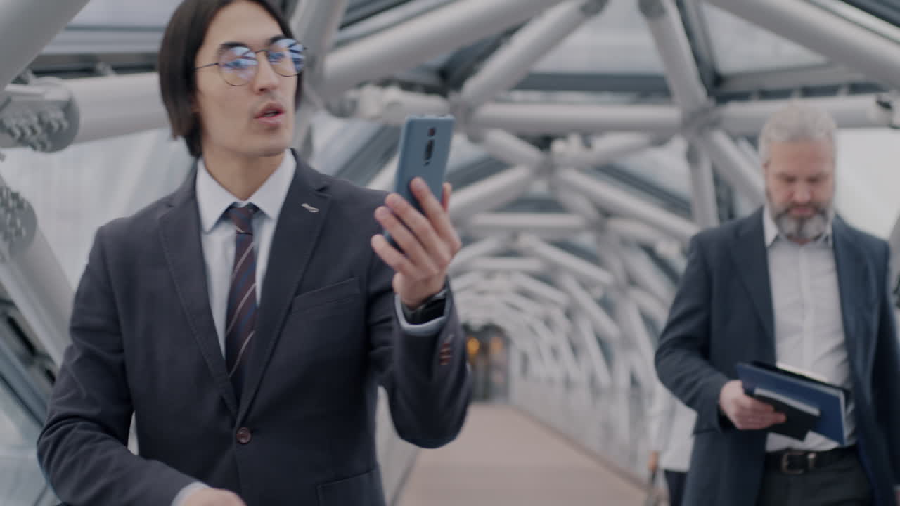 Businessmen using smartphones on a city bridge