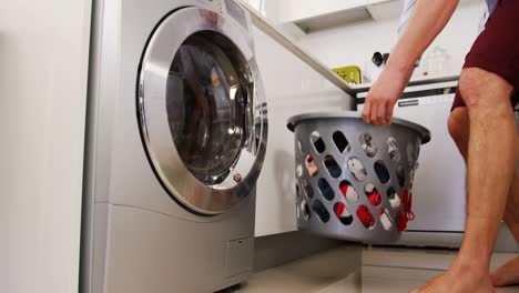 Man-putting-his-clothes-into-washing-machine