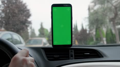 una maqueta de teléfono inteligente de pantalla verde dentro del coche durante la conducción.