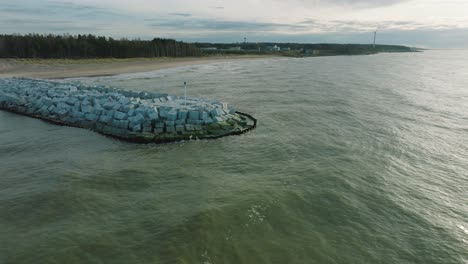 Vista-Aérea-Del-Muelle-Protector-Con-Bloques-De-Hormigón-Y-Rocas-En-La-Costa-Del-Mar-Báltico-En-Liepaja,-Letonia,-Fortaleciendo-La-Playa-Contra-La-Erosión-Costera,-Tiro-Ascendente-De-Drones-Avanzando