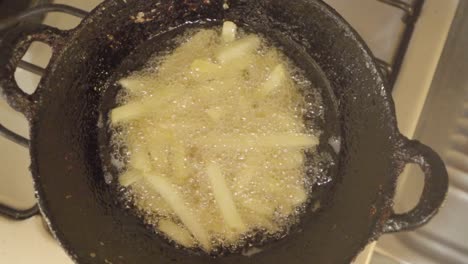 homemade french fries deep frying in vegetable oil in hot wok, overhead view