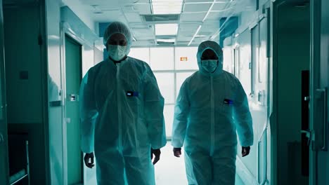 two doctors in protective gear walking through a hospital corridor