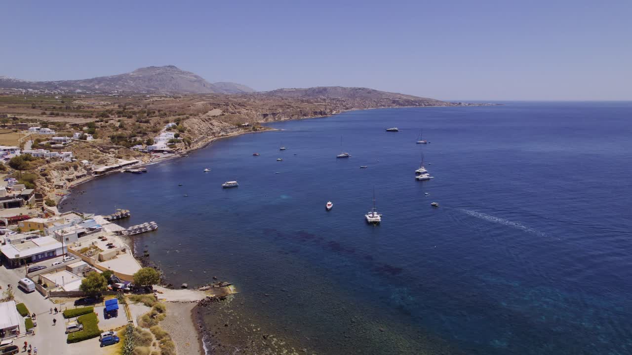 Aerial View of the Aegean Sea Coastline in Santorini, Greece with Boats and Parked Cars