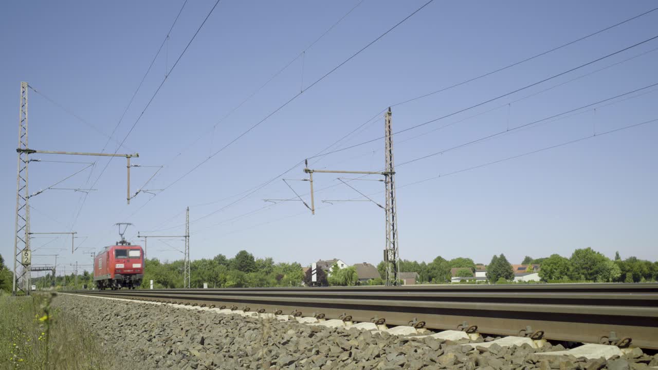 высокоскоростный ледяный поезд, проходящий мимо на рельсах в солнечной сельской местности, ярко-голубое небо над головой, динамичный съемка движения
