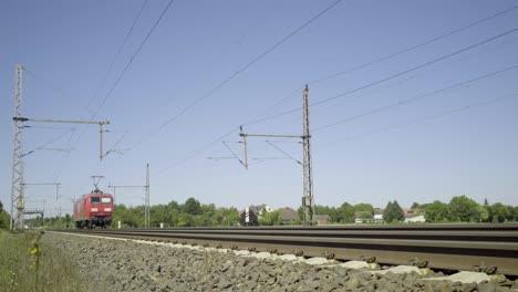 Hochgeschwindigkeits-Eiszug,-Der-Auf-Gleisen-In-Einer-Sonnigen-Ländlichen-Umgebung-Vorbeirauscht,-Strahlend-Blauer-Himmel-über-Uns,-Dynamische-Bewegungsaufnahme