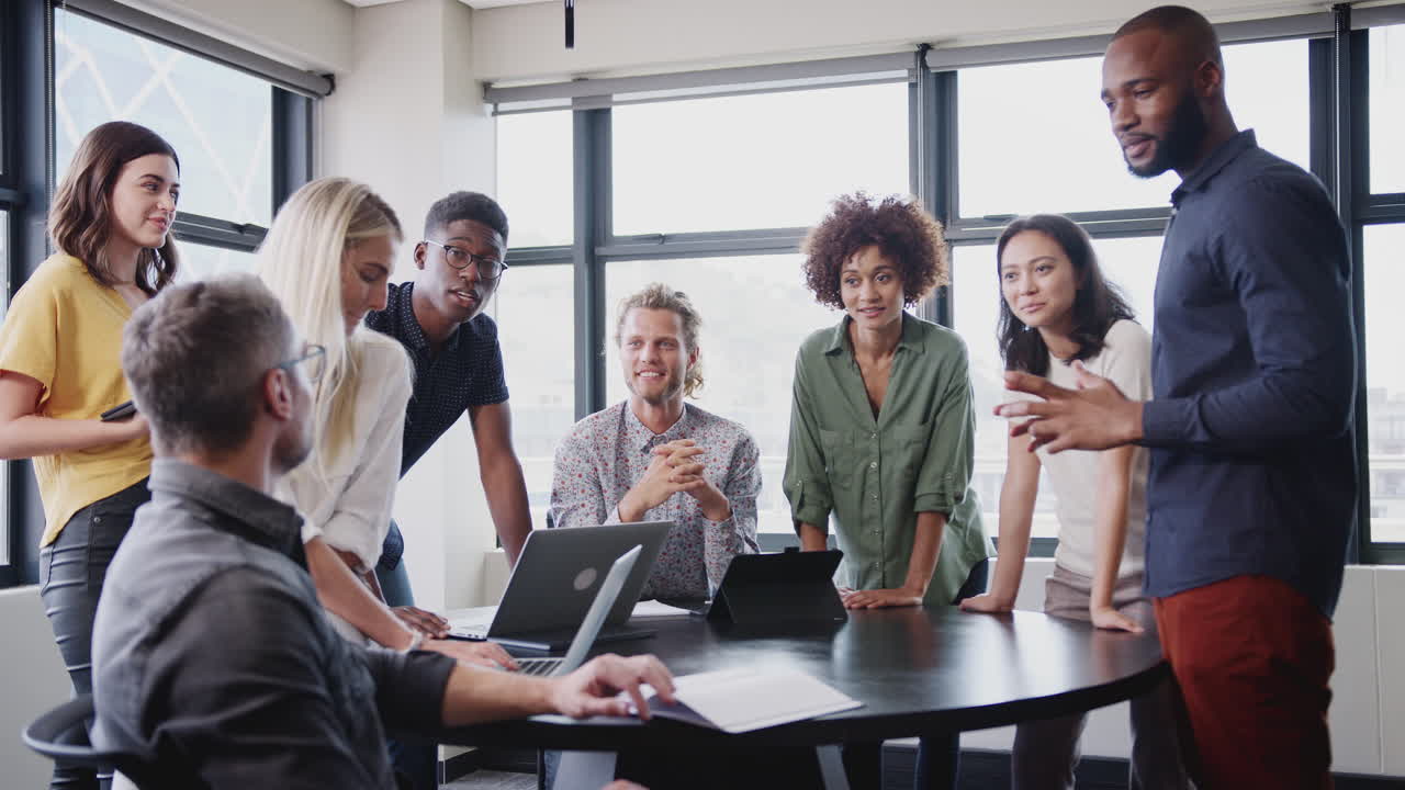 Happy creative team in a meeting room listening to their manager before a brainstorm, low angle