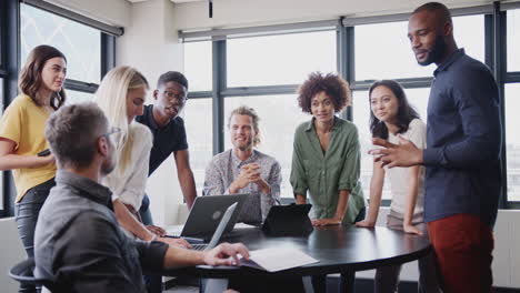 happy creative team in a meeting room listening to their manager before a brainstorm, low angle