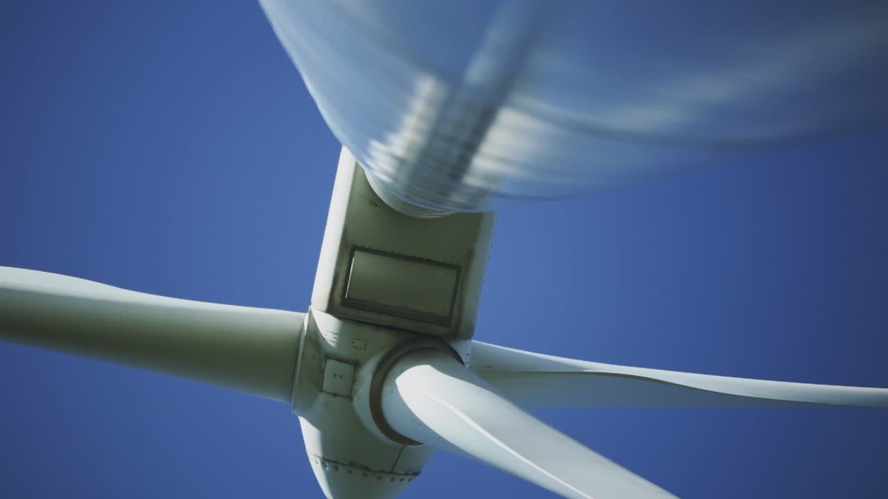 Afternoon underneath perspective and panning footage from a wind turbine machine and its rotating blades