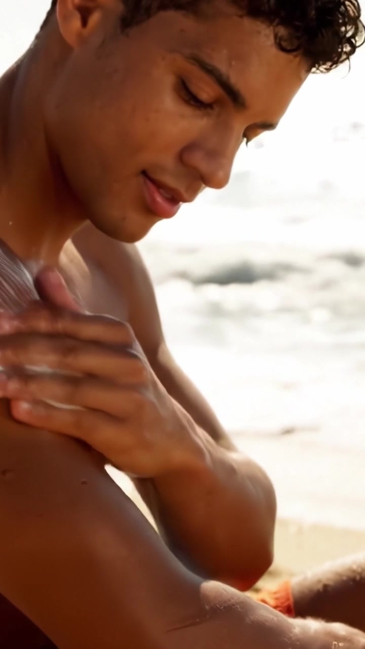 A Young Man Applying Sunscreen at the Beach, Enjoying the Sun while Taking Precautions for Skin Protection and Health