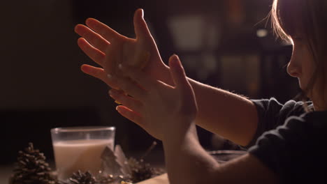little girl child rolling raw cookie dough in hands. close up side view handheld