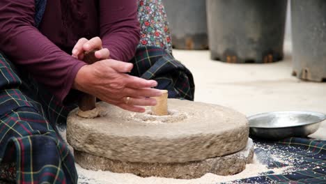 the old woman is grinding flour in the stone mill with the old traditional method. millstones for grinding wheat into flour, mill traditional production.