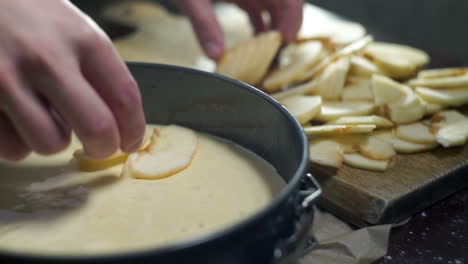 Man-making-apple-pie.-Cook-puts-apple-slices-into-baking-pan.-Closeup