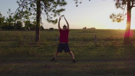 young man doing stretching exercises to relax and get fit in nature at sunset