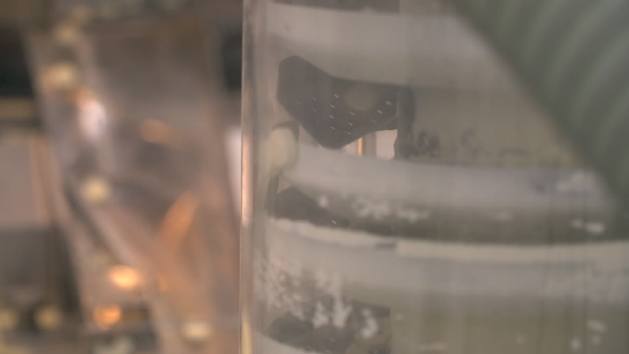 Pharma laboratory assembly line of round pills down ramp to vertical tower, rack focus close up