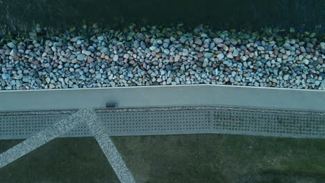 the concrete pedestrian way along the stony baltic sea beach coastline in westerplatte, poland aerial top-down view daytime