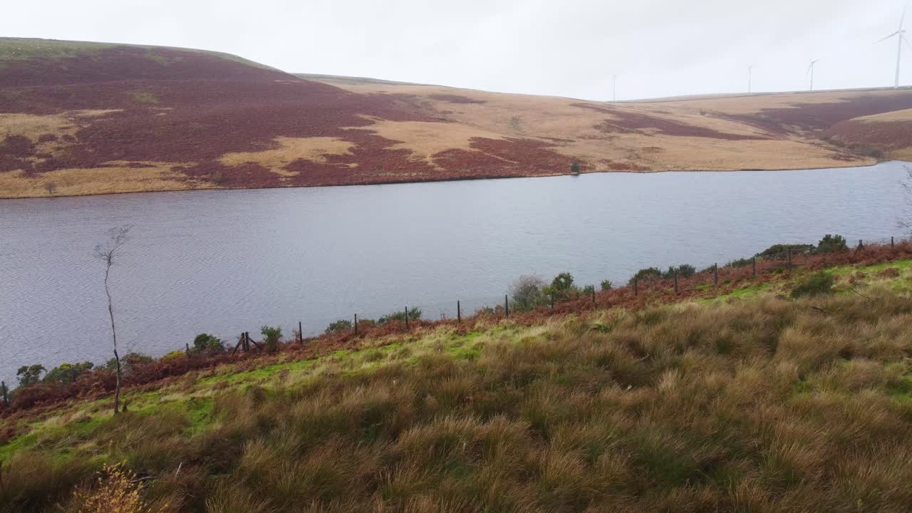 Reservoir with Wind Turbines as Aerial Drone shot Pushes Forward with Path and Fence Visible Wales UK 4K