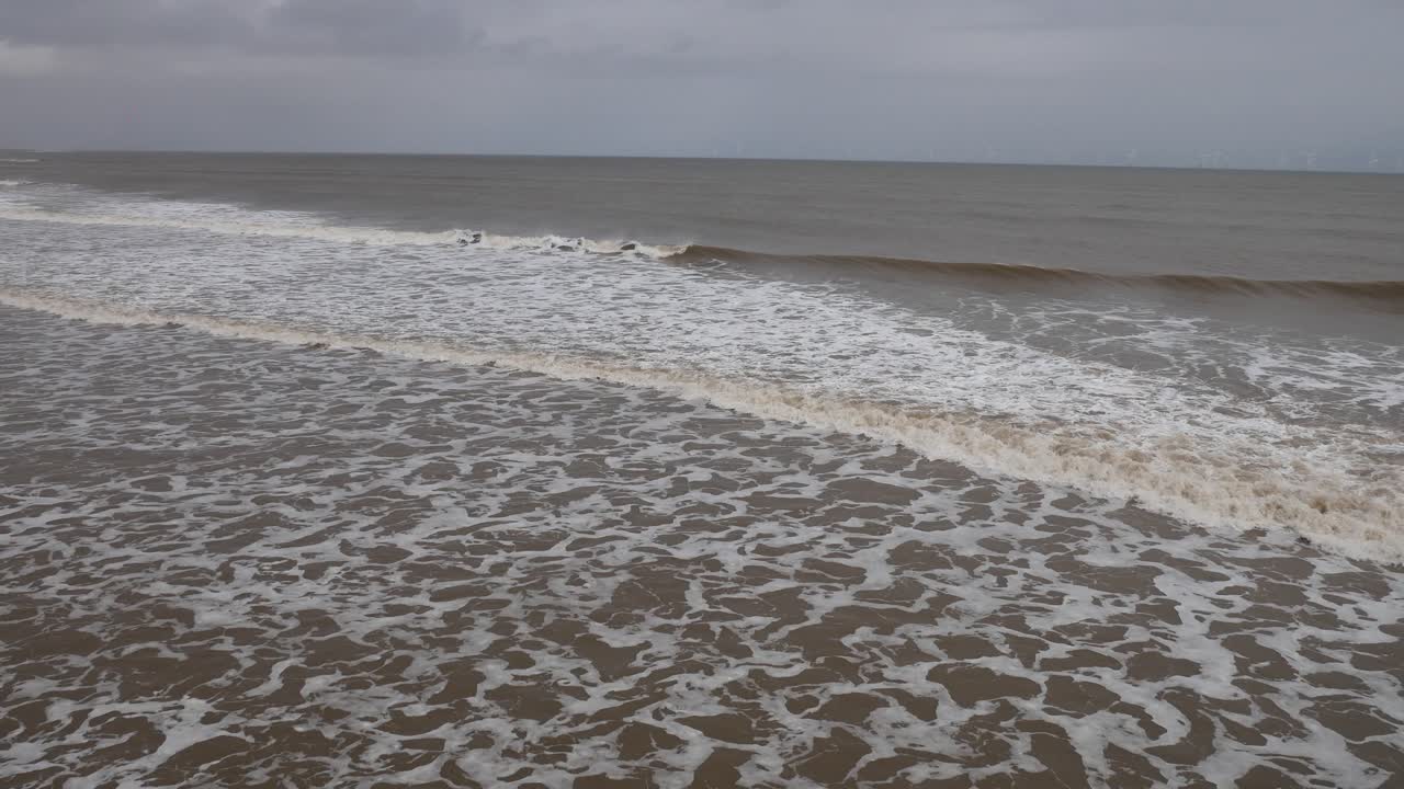 las suaves olas del océano del mar del norte rodando en la orilla en la playa con olas blancas en un día gris en la costa inglesa