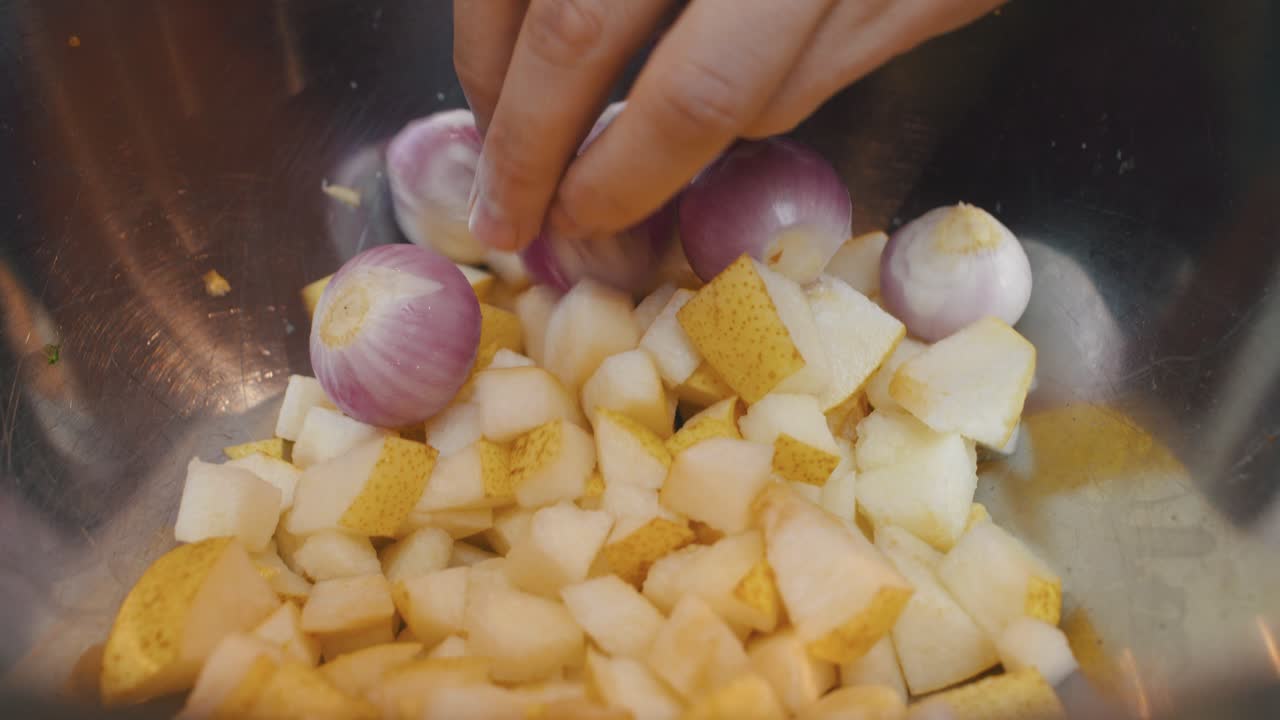 Adding pear, onion and garlic ingredients into deep metal cooking bowl