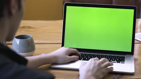 person working on a laptop with a green screen