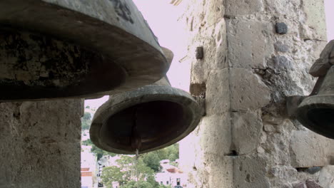 campanas de iglesia montadas en una torre alta en la plaza pública de un pequeño pueblo mexicano, que pueden ser escuchadas por la comunidad circundante