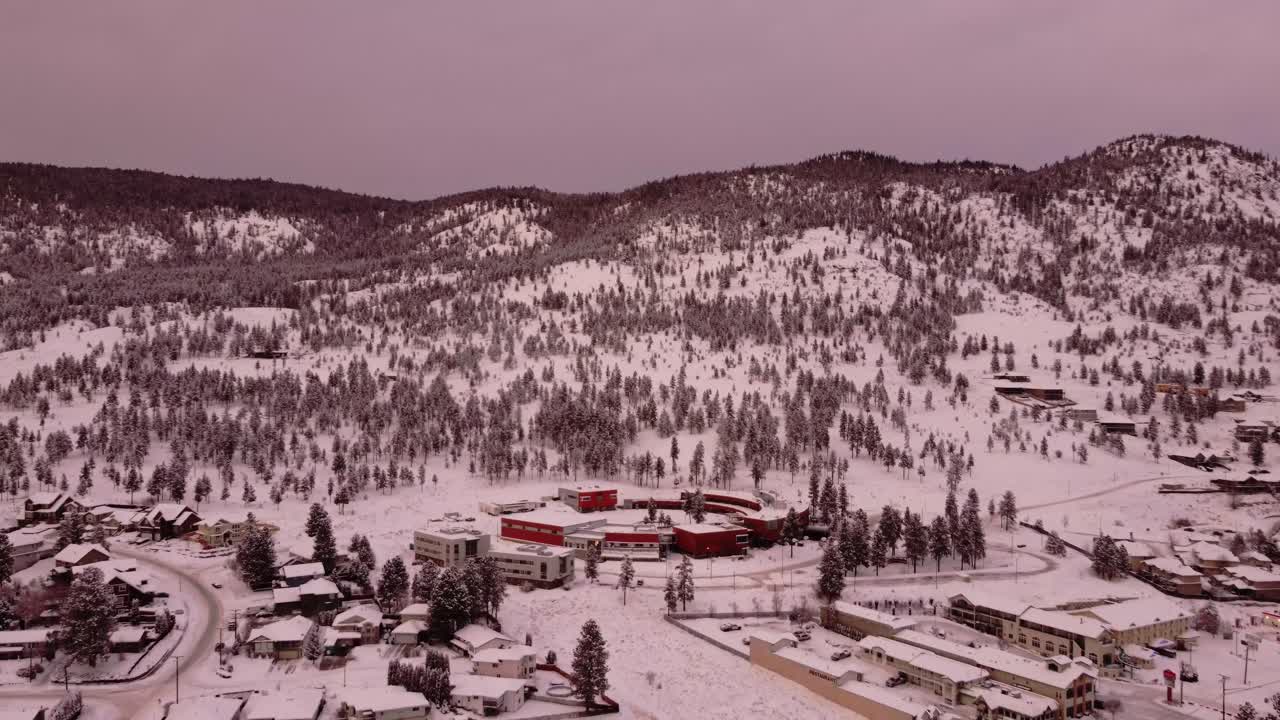 un edificio circular se encuentra junto a un denso bosque y montañas cubiertas de nieve en la ciudad de merritt, columbia británica