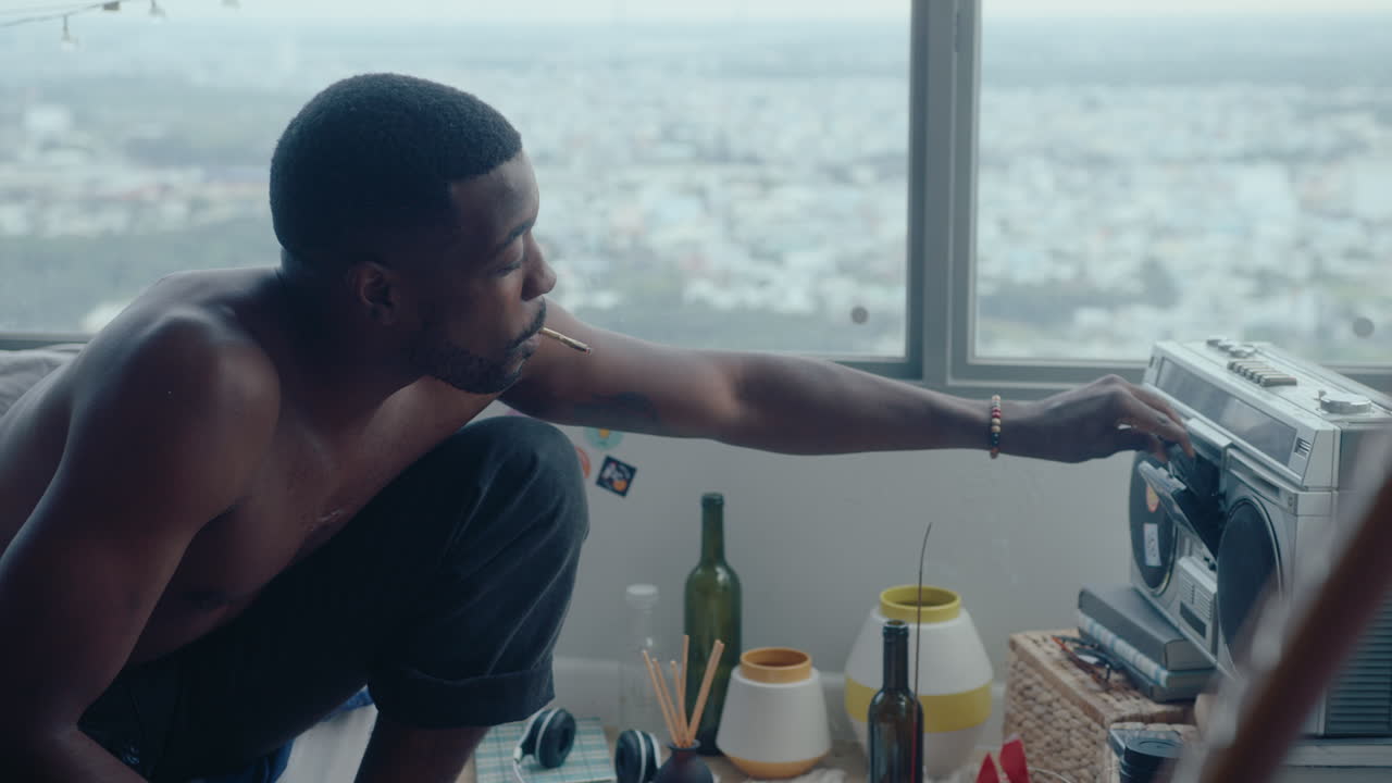 Young Man Smoking and Listening to Music with Girlfriend in Bedroom