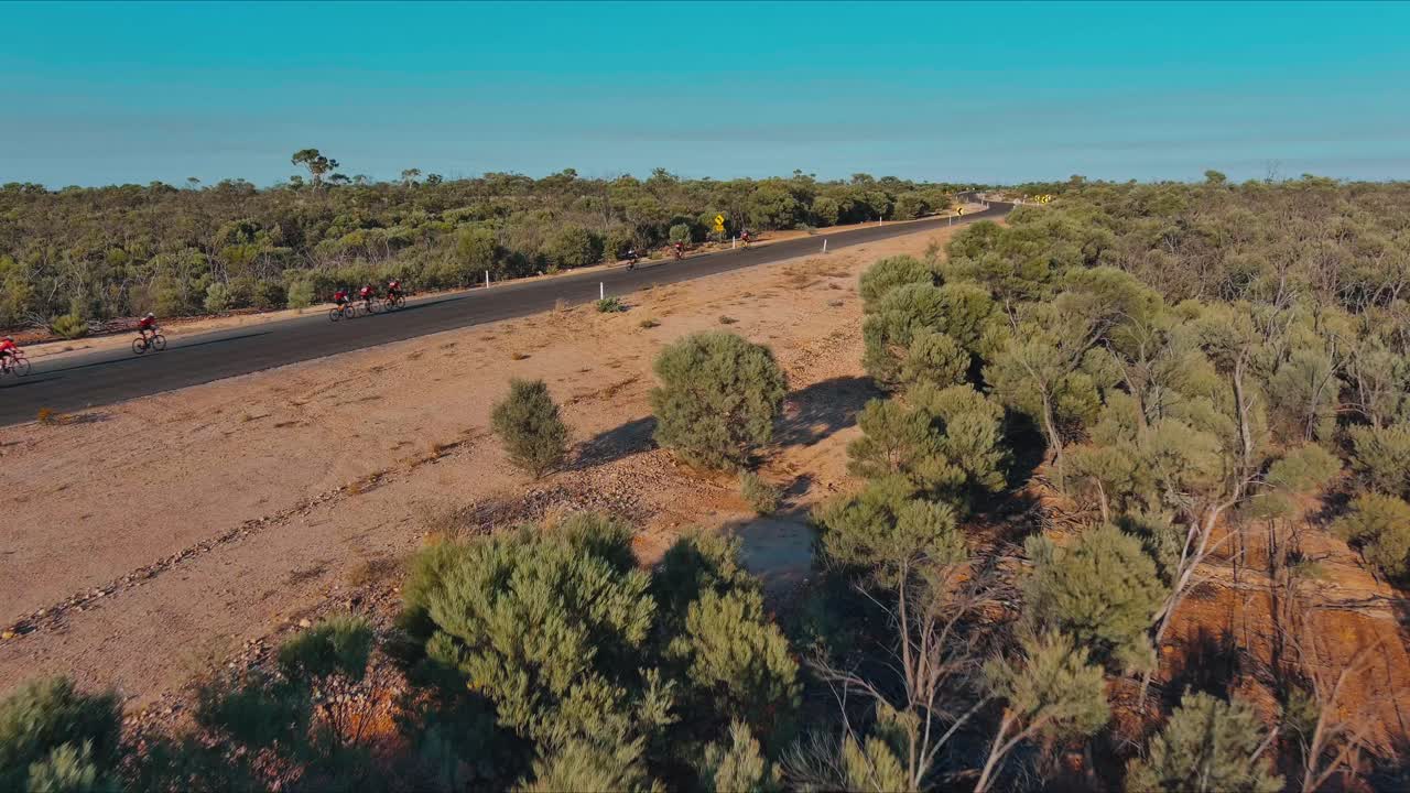 Aerial View, Cyclists riding on a highway in Winton, Queensland with the dry dusty outback surrounding them