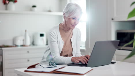 senior, woman and working in kitchen on laptop