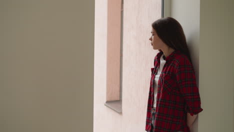 sad woman hides in window arch from bullies. pensive lady deals with cruel attitude from aggressive groupmates at college. mental health problems