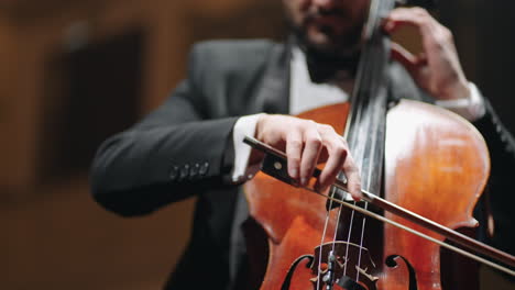 inspired musician is playing cello in opera house hall rehearsal or concert of classical music closeup view