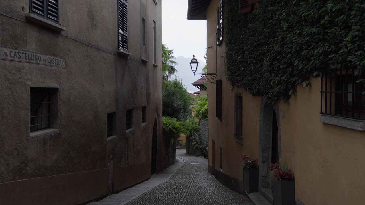 Stretta strada acciottolata a Menaggio, Italia, vicino alle rovine del castello medievale.