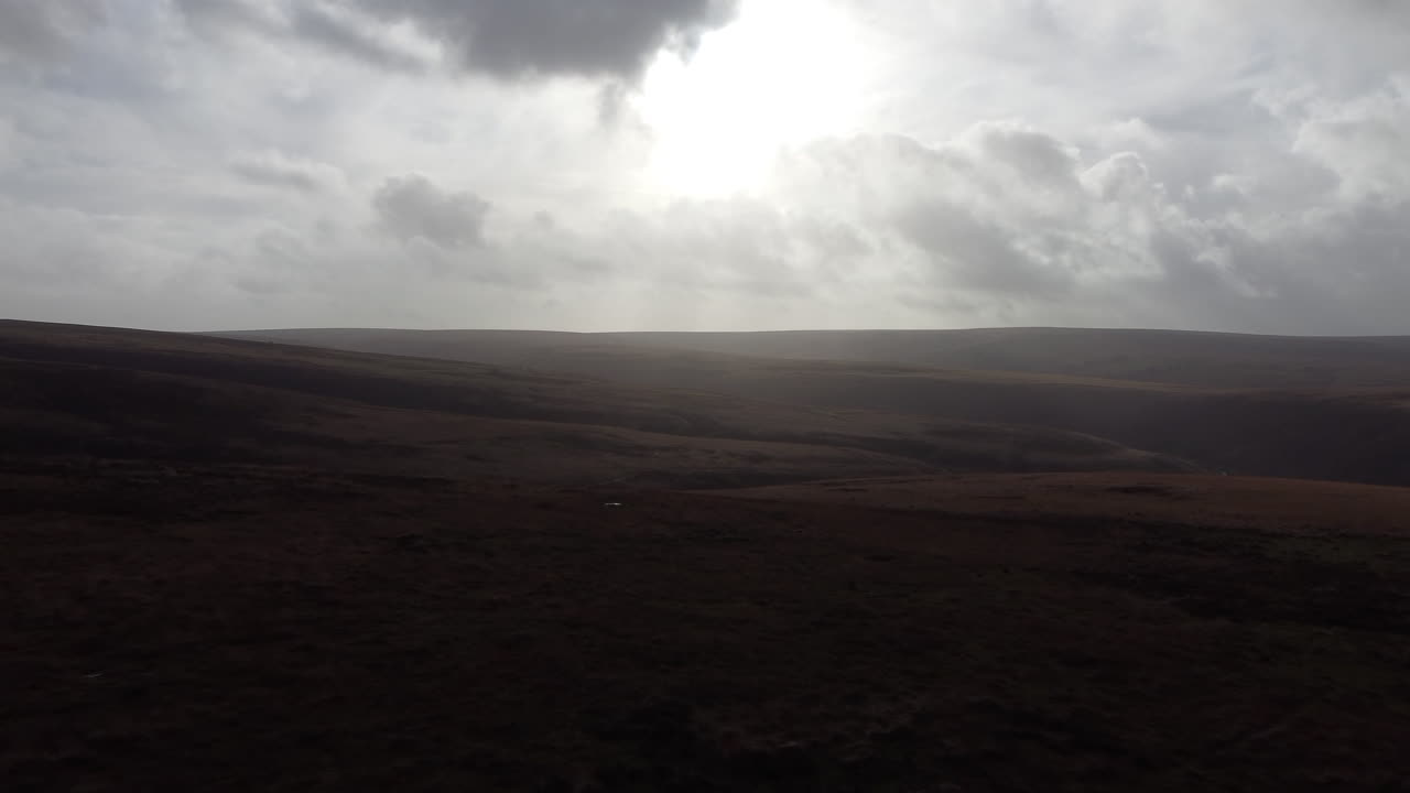 Aerial View Over Open Countryside Moorland with Hazy Cloudscape and Sun Flare in Exmoor - Drone Shot UK 4K