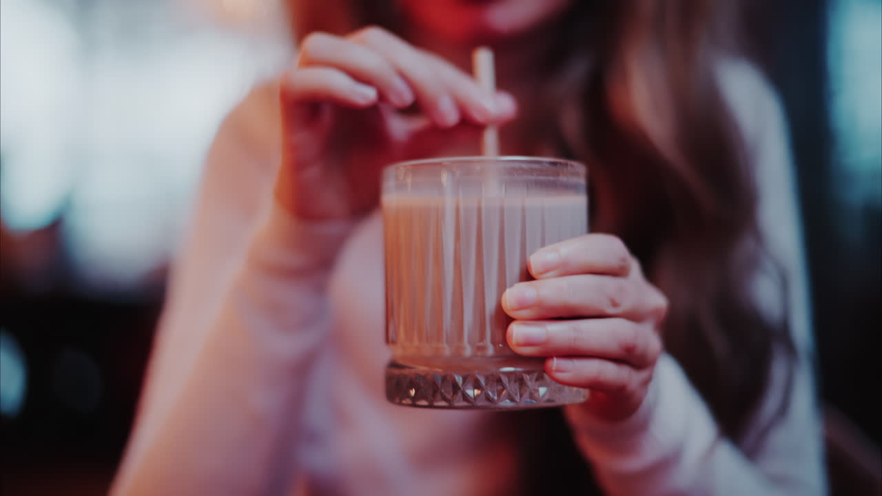 Close up of a woman drinking hot chocolate with a straw at a cafe