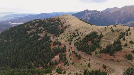 aerial dolly to exposed mountain peak with sparse forest up along dirt road