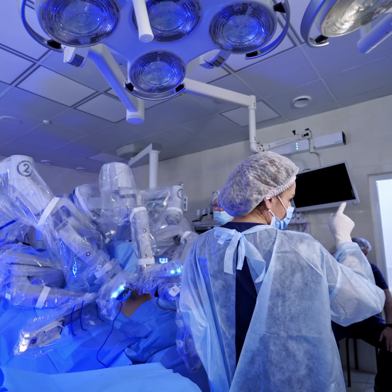 Robotic equipment in the modern hospital. Minimally invasive surgery without doctors involvement. Group of doctors observe the robotic process.
