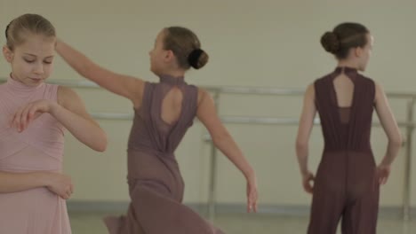 a group of young ballet students in black dancewear practicing positions in a spacious ballet studio with wooden flooring and wall-mounted barres. focused expressions and synchronized movements.