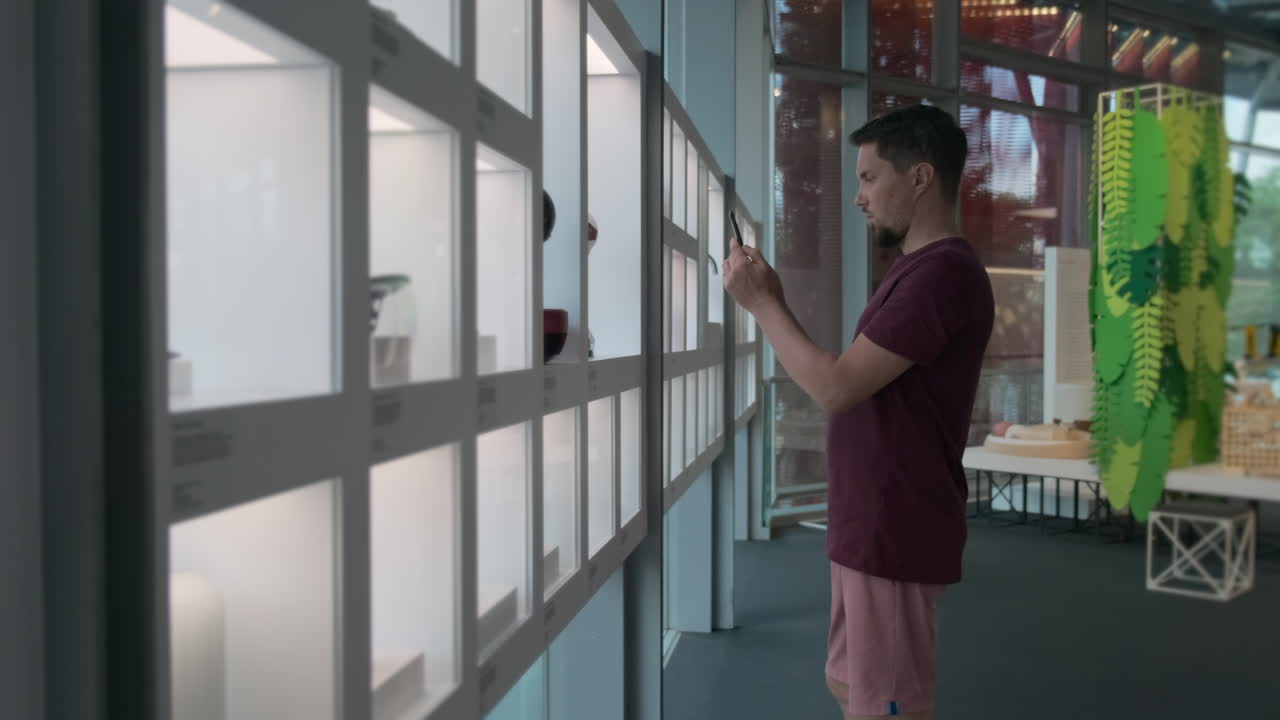 hombre tomando una foto de objetos de diseño en una exposición de museo