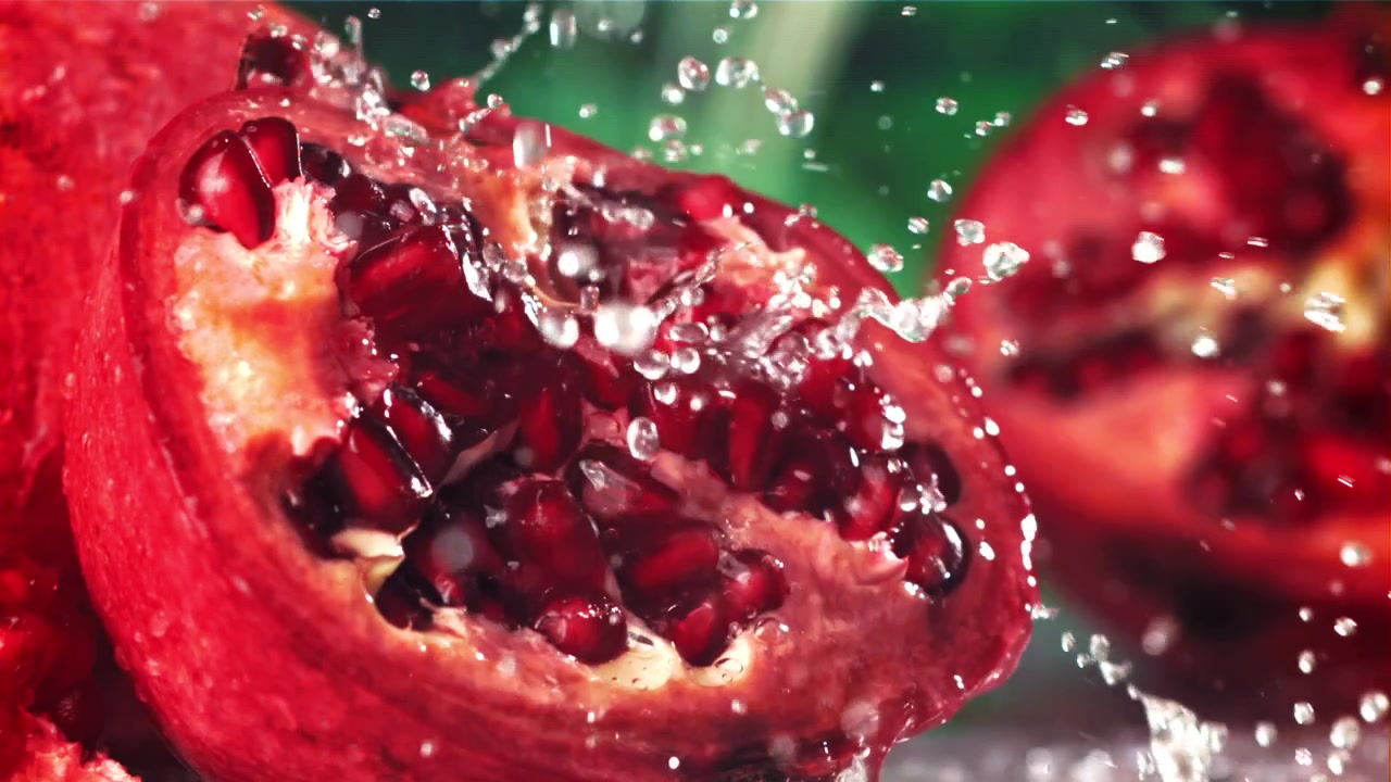 Vand sprøjter på en frisk rød granatæblehalvdel i slowmotion