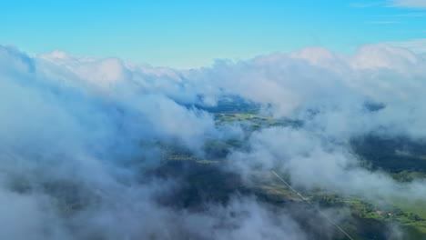 a smooth aerial shot of the clouds in the blue sky and a green landscape