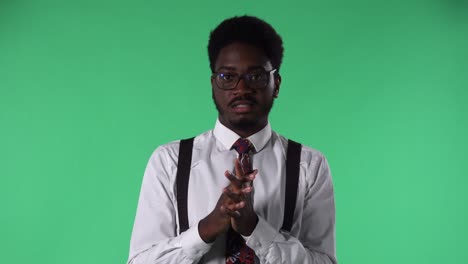 portrait of young african american man reporting of interesting information and gesturing with his hands. black male with tie and glasses in white shirt posing on green screen in studio. close up
