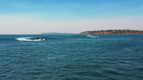 ocean aerial view of jet ski's towing hydro foil athletes into ocean wave together