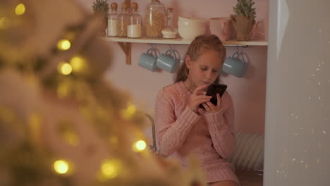 little girl uses her phone to send merry christmas messages at home