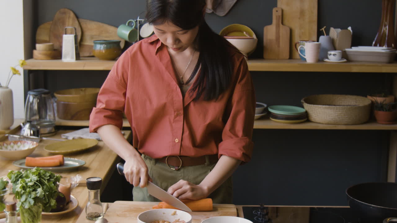 Young Woman Chopping Carrots in Her Modern Kitchen
